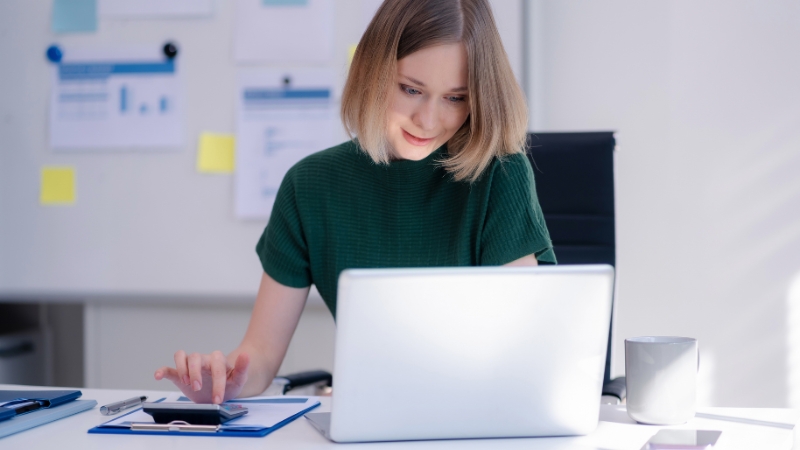 Preduzetnica za laptopom i kalkulatorom planira troškove prilikom procesa otvaranja firme