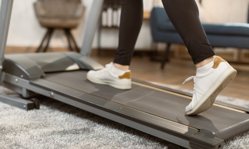 Osoba koja nosi bele patike hoda na traci za trčanje