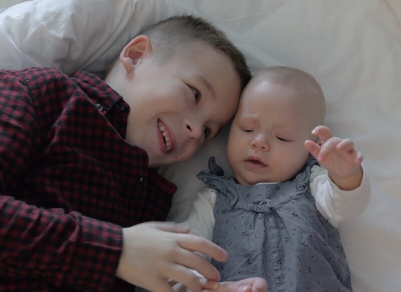 dva deteta na krevetu, beba i malo stariji brat se igraju