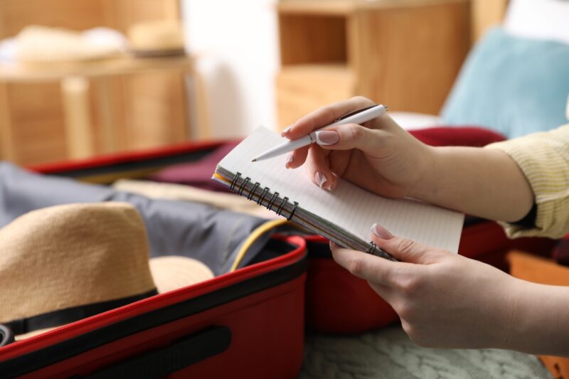 devojka pravi listu za pakovanje za putovanje