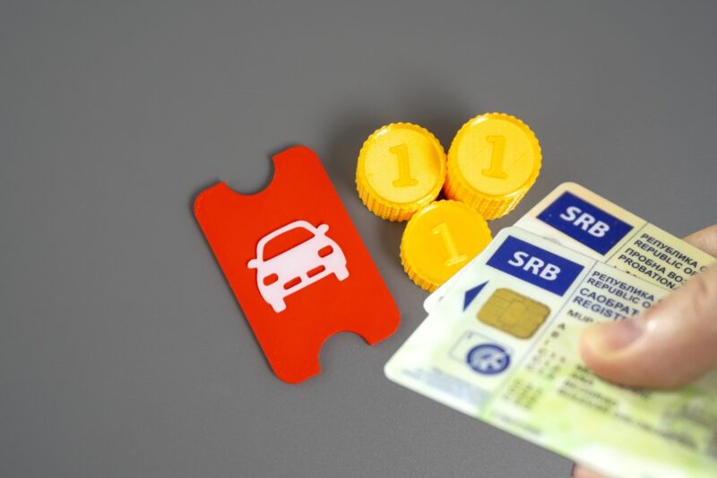 saobraćajna dozvola, novac i auto na papiru u pozadini