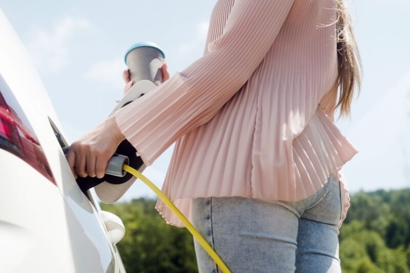 devojka uključuje auto na punjenje