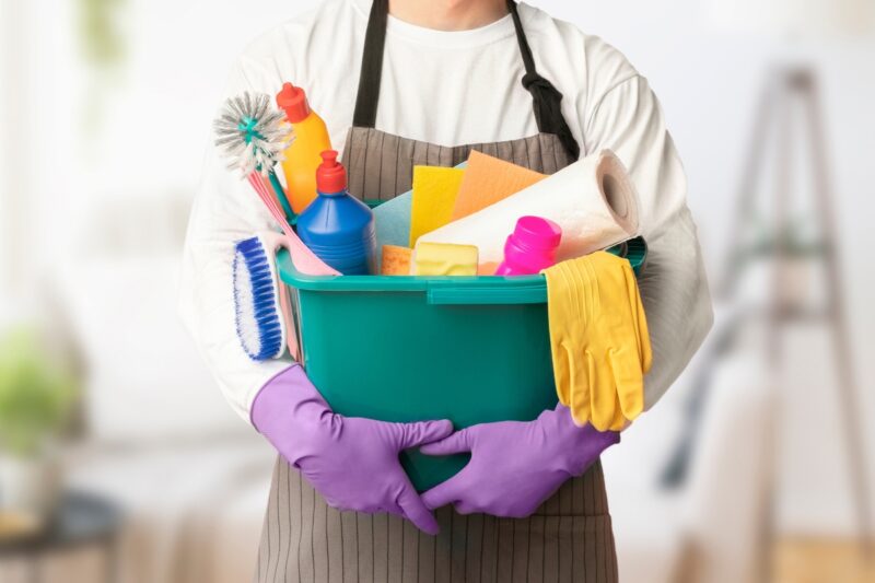 devojka drži u rukama kantu u kojoj je hemija i sredstva za čišćenje