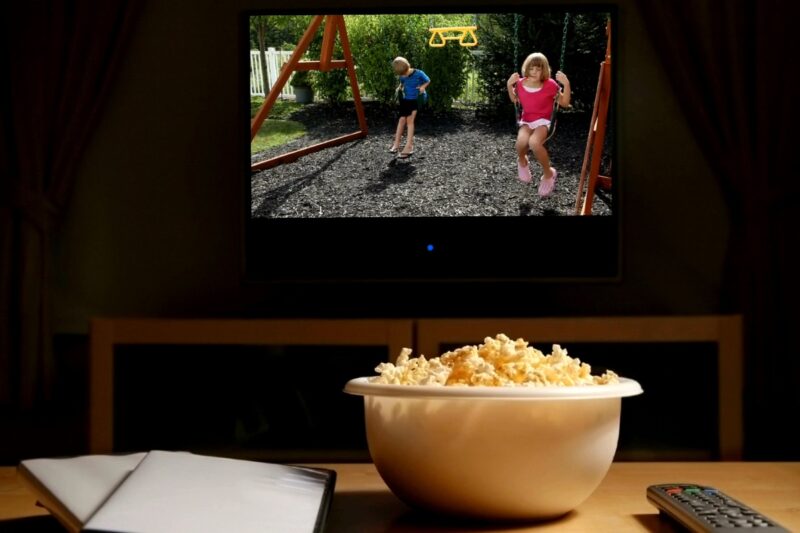 kokice na stolu i daljinski, u pozadini televizor na kom se emituje neki film ili serija