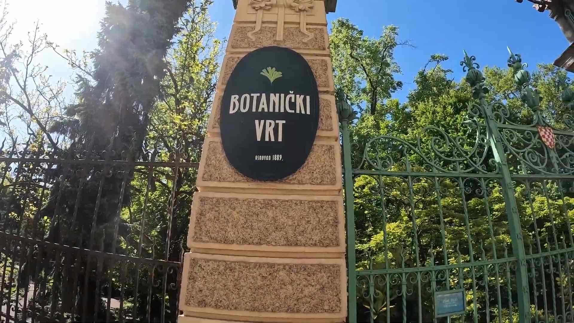 Ulazna kapija i tabla Botaničkog vrta u Zagrebu okružena zelenilom