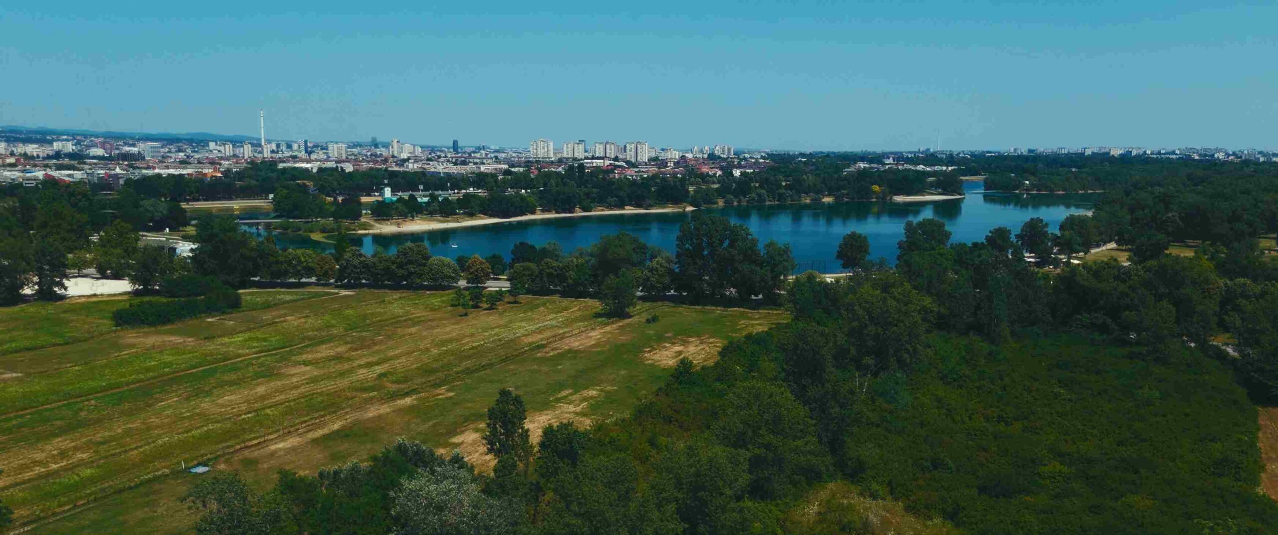 Panoramski pogled na jezero Jarun, okolno zelenilo i grad Zagreb u daljini