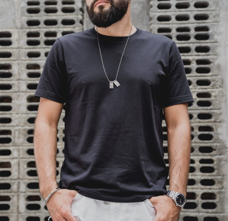 Muška dog tag ogrlica preko crne majice u streetwear kombinaciji
